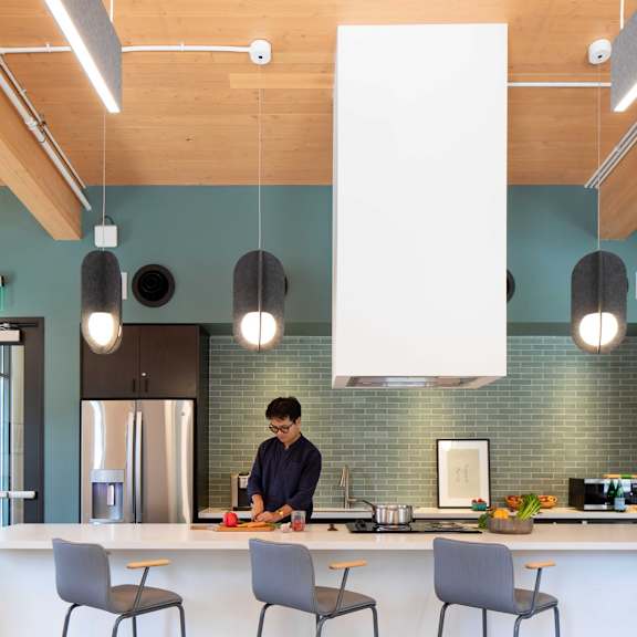 a kitchen with a person cooking and three bar stools.