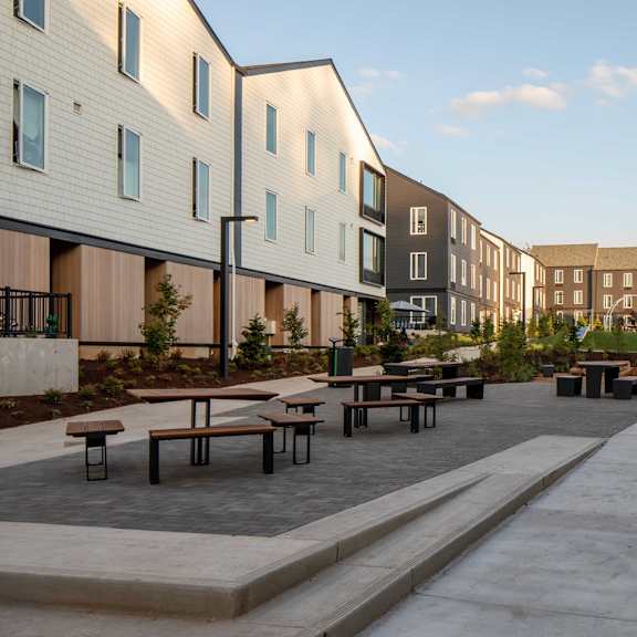 a long concrete walkway leads between two rows of modern buildings.