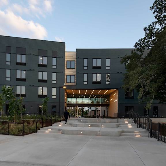 a modern building with a black exterior and a large open courtyard in front.