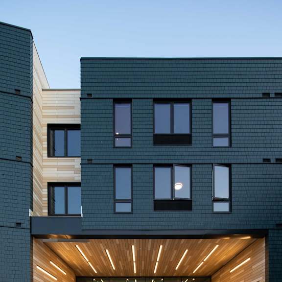 a modern building with a black facade and a wooden entrance.