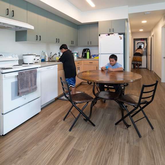 a man and a boy are in a kitchen with a table and chairs.