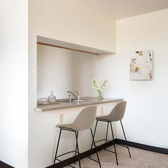 a small kitchen with a counter and two stools