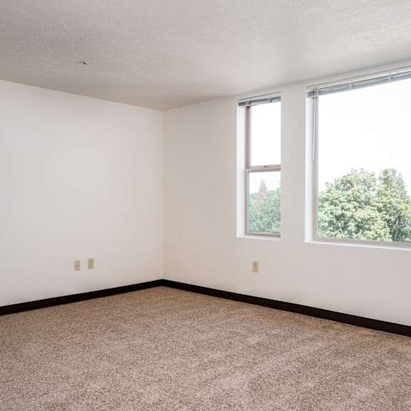 an empty room with two windows and a carpeted floor
