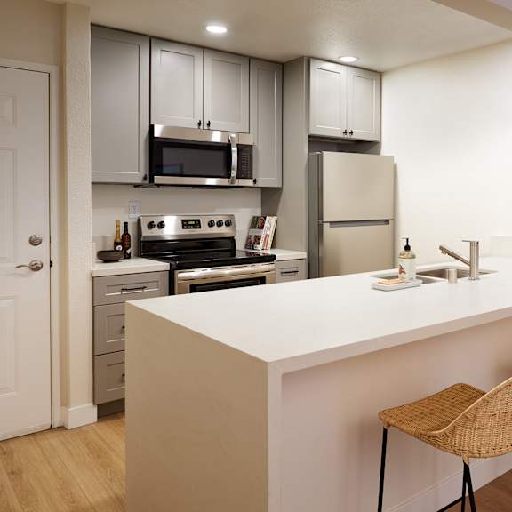 a kitchen with a white countertop and two wicker chairs.
