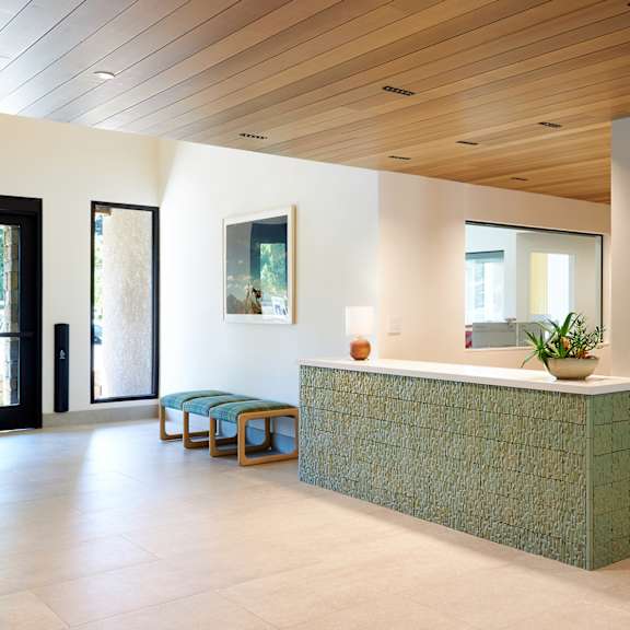 a reception area with a green reception desk and a wooden ceiling.
