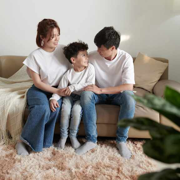 a family of three is sitting on a beige couch.