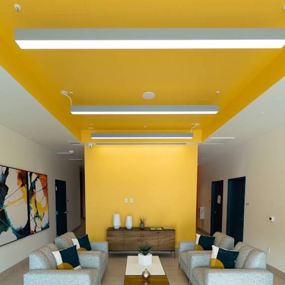 a brightly lit living room with a grey sofa and a coffee table.