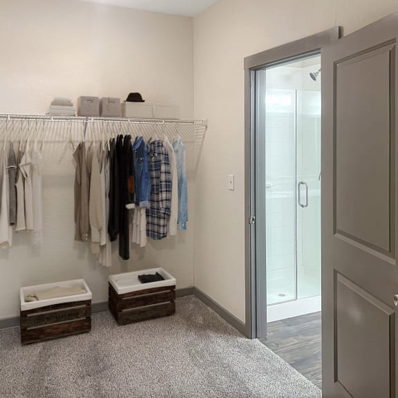 Thumbnail 4 of 5 a walk in closet with clothes hanging on a rack and a closet door to a