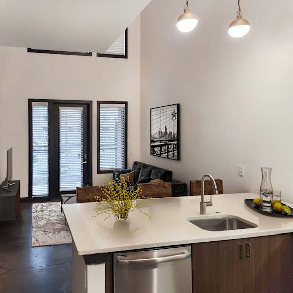 Thumbnail 1 of 7 A kitchen with a white counter top and a stainless steel dishwasher.
