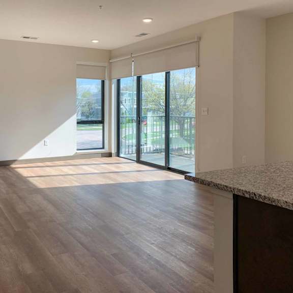 Thumbnail 26 of 36 a living room with several large windows a sliding glass doors to a balcony