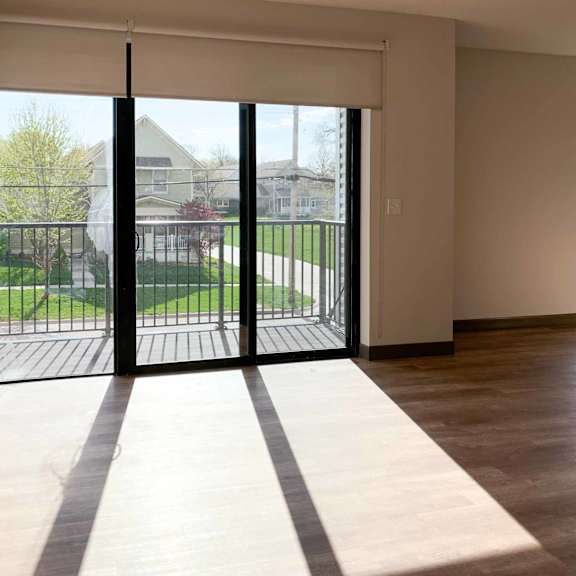 Thumbnail 27 of 36 a living room with hardwood floors and large sliding glass doors to the balcony