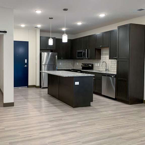 Thumbnail 3 of 15 a kitchen with dark cabinets and light granite countertops
