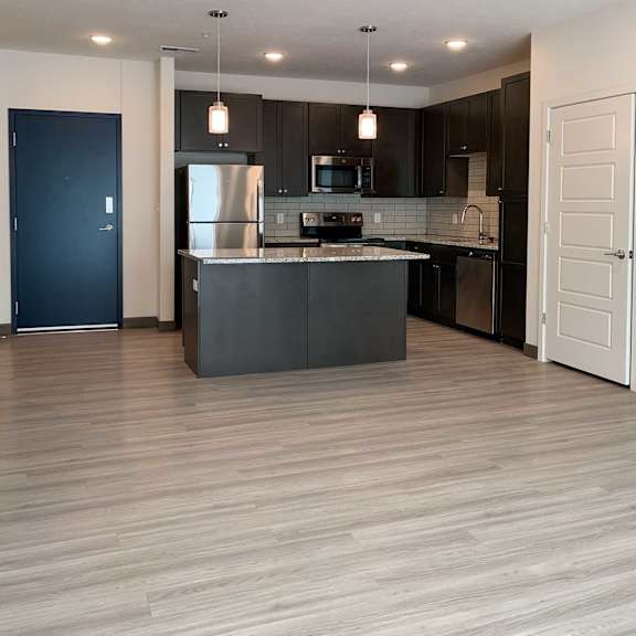 Thumbnail 5 of 13 a living room and kitchen with dark cabinets and light granite