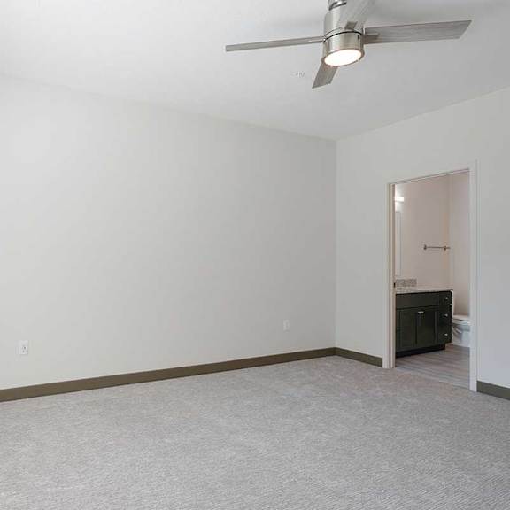 Thumbnail 23 of 29 a bedroom with carpet, a stainless steel ceiling fan, and an attached bathroom