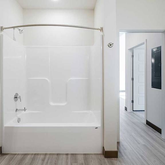 Thumbnail 15 of 29 a large shower tub with a curved shower curtain next to a closet and a door to the living area