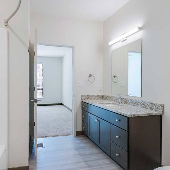 Thumbnail 25 of 29 a bathroom with a granite vanity sink, toilet, and a mirror