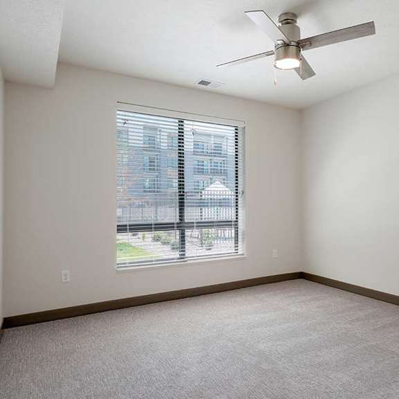 Thumbnail 13 of 29 a bedroom with carpet, a large window, and a stainless steel ceiling fan