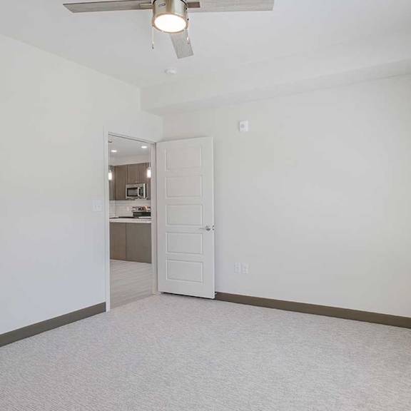 Thumbnail 12 of 29 a bedroom with a door to the living room and a ceiling fan