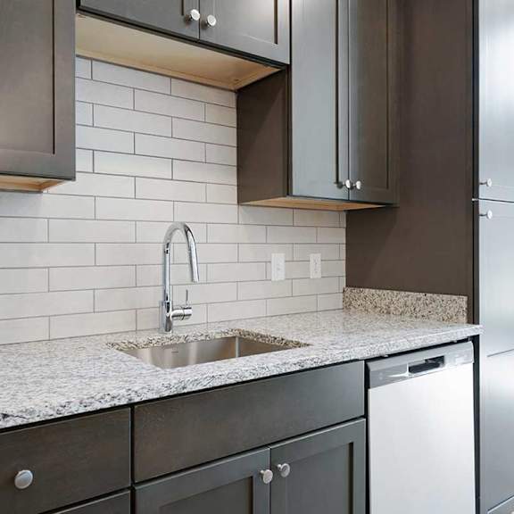 Thumbnail 5 of 29 a kitchen sink with dark cabinets, granite countertops, and a white tile backsplash