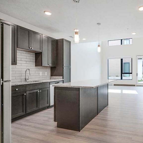 Thumbnail 3 of 29 a kitchen with dark cabinets and a large island in front of a living room/dining room area