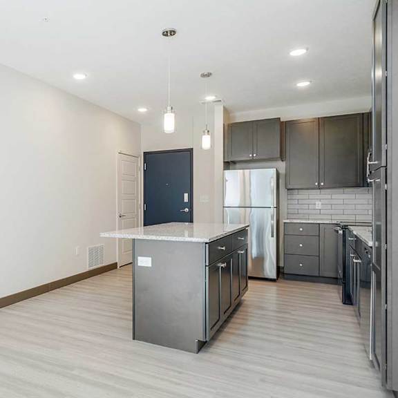 Thumbnail 11 of 29 a kitchen with dark cabinets next to a blue front door and staircase