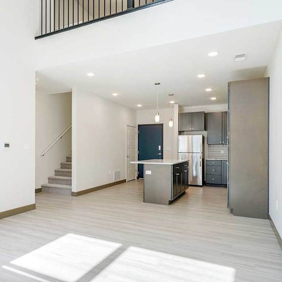 Thumbnail 10 of 29 a living room facing a kitchen with dark cabinets and a staircase