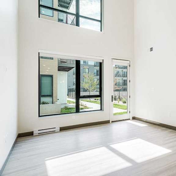Thumbnail 7 of 29 a living room with a two-story wall of windows and luxury vinyl tile flooring