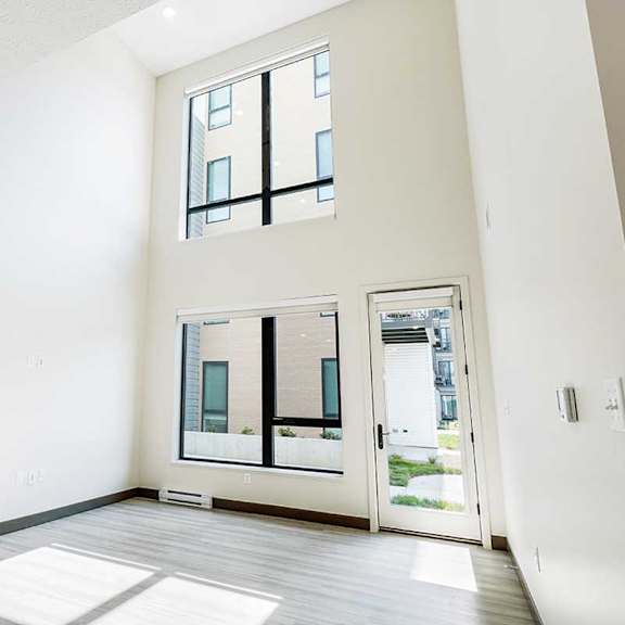 Thumbnail 8 of 29 a living room with a two-story wall with large windows and a door to a patio