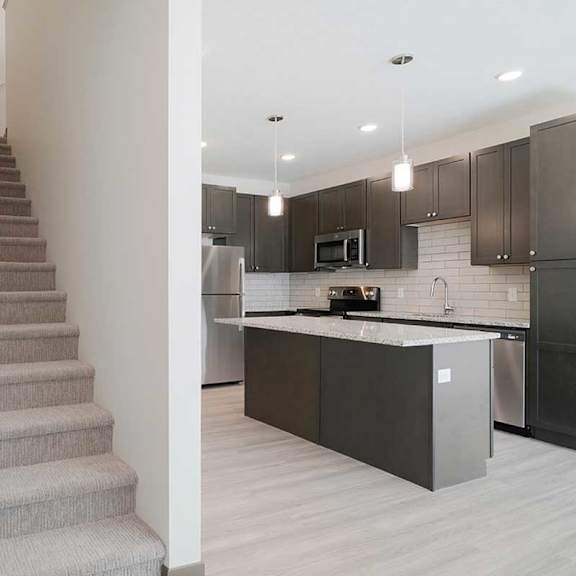 Thumbnail 18 of 29 a carpeted staircase next to a kitchen with dark cabinets