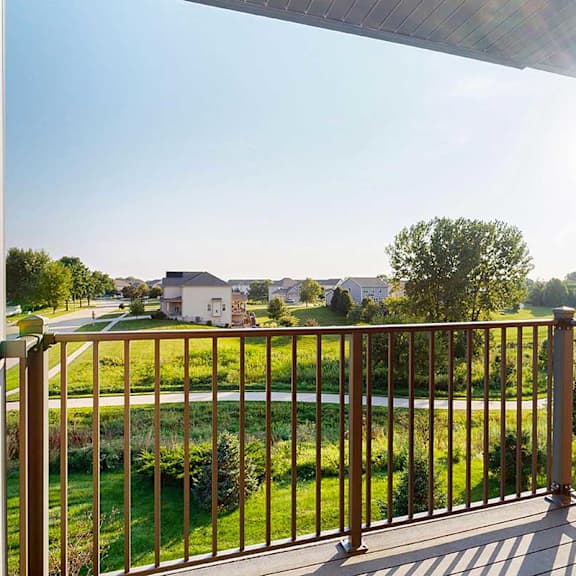 Thumbnail 17 of 26 A balcony with a view of a green space, with houses in the distance.
