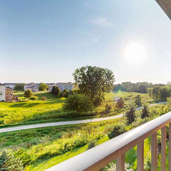 Thumbnail 18 of 26 A balcony overlooks a green landscape with houses in the distance.