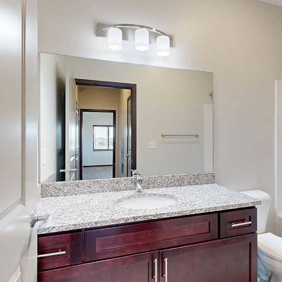 Thumbnail 24 of 26 A bathroom with a granite countertop and a large mirror.