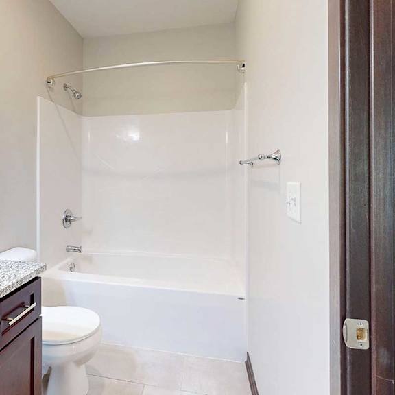 Thumbnail 25 of 26 A bathroom with a granite vanity sink and a tub shower with a curved curtain rod.