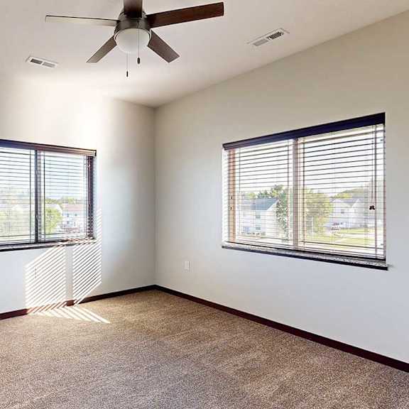 Thumbnail 22 of 26 A bedroom with a ceiling fan, and two windows - one on each wall.