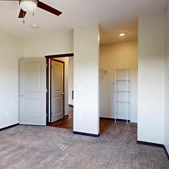 Thumbnail 21 of 26 A bedroom with a ceiling fan, a large window, and a walk-in closet.