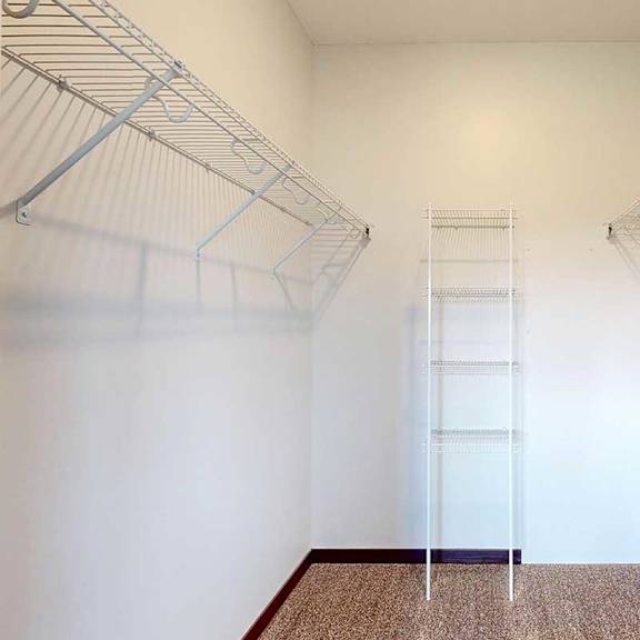 Thumbnail 23 of 26 A walk-in closet with shelves and a carpeted floor.