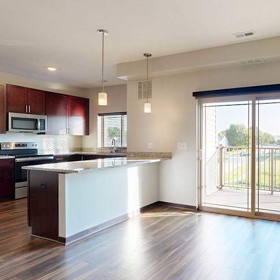 Thumbnail 16 of 26 A dining area with a peninsula counter from the kitchen, and a large sliding glass door to a balcony.