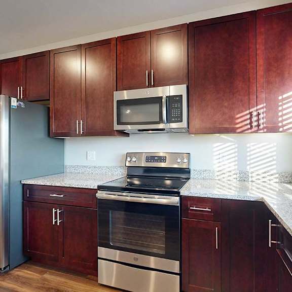 Thumbnail 12 of 26 A modern kitchen with dark wooden cabinets, granite countertops and stainless steel appliances.