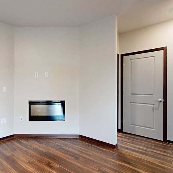 Thumbnail 7 of 26 A living room with an electric fireplace and hardwood flooring.