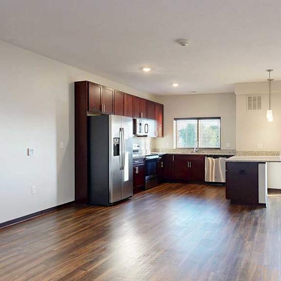 Thumbnail 9 of 26 An open-concept kitchen with dark wooden cabinets, granite countertops, stainless steel appliances, a window above the sink, and a peninsula counter.