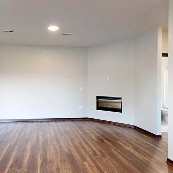 Thumbnail 6 of 26 A living room with an electric fireplace and hardwood flooring.
