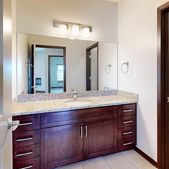 Thumbnail 28 of 29 A bathroom with a granite vanity sink and a partitioned off shower room.