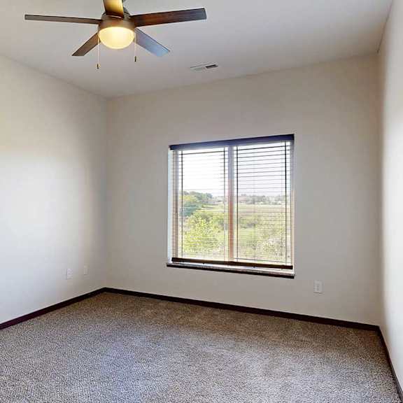 Thumbnail 21 of 29 A carpeted bedroom with a large window and a ceiling fan.