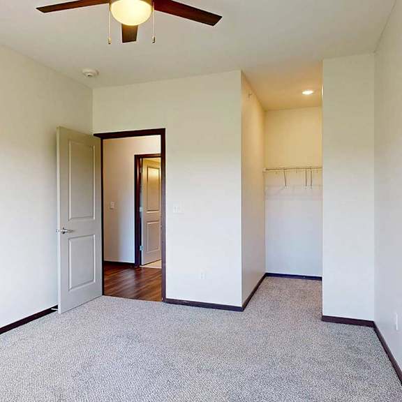 Thumbnail 22 of 29 A bedroom with a ceiling fan, and an open walk-in closet.