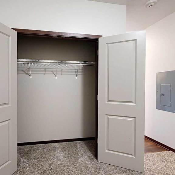 Thumbnail 25 of 29 A den space with a carpeted floor and a double door closet, perfect for an at home office.