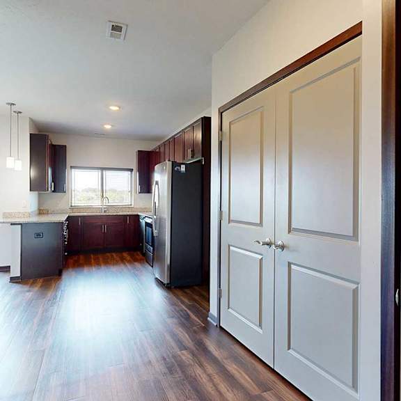 Thumbnail 6 of 29 A front entryway opening to a kitchen, with two closets on the right.