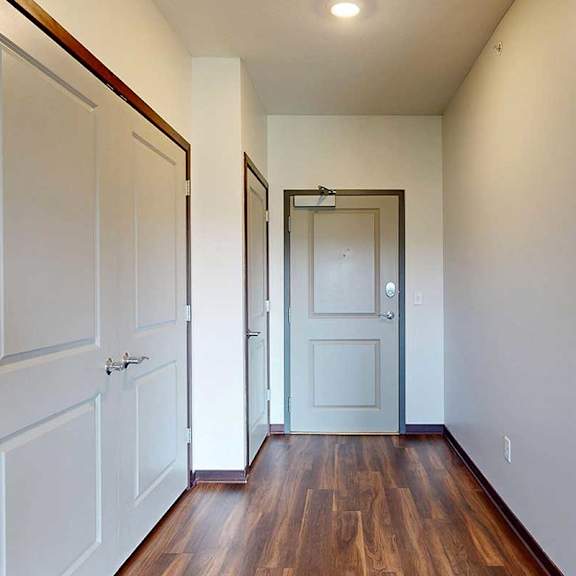 Thumbnail 3 of 29 A hallway leading from the front door to the kitchen, with two closets on the left.