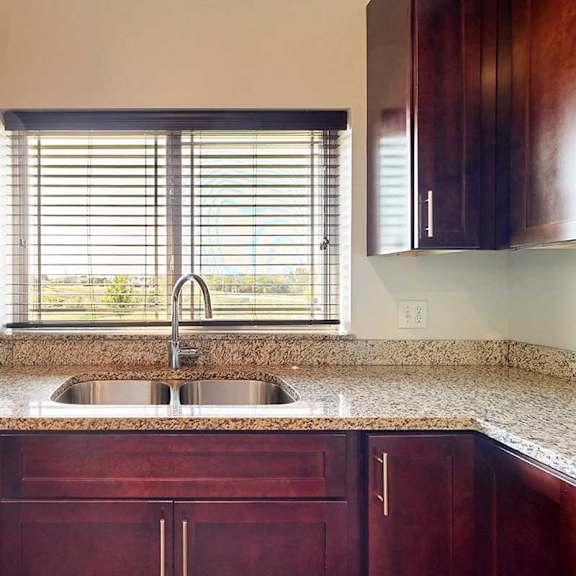 Thumbnail 11 of 29 A kitchen with a stainless steel sink, granite counters, and a window above the sink.