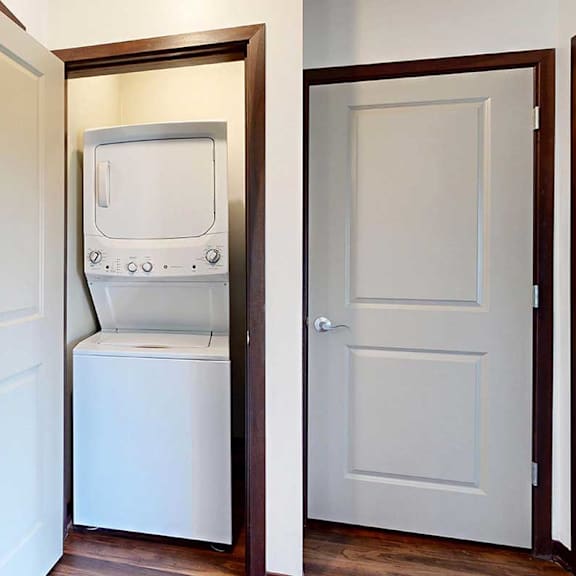 Thumbnail 27 of 29 A stacked wash and dryer in a closet in the hallway next to the bathroom door.