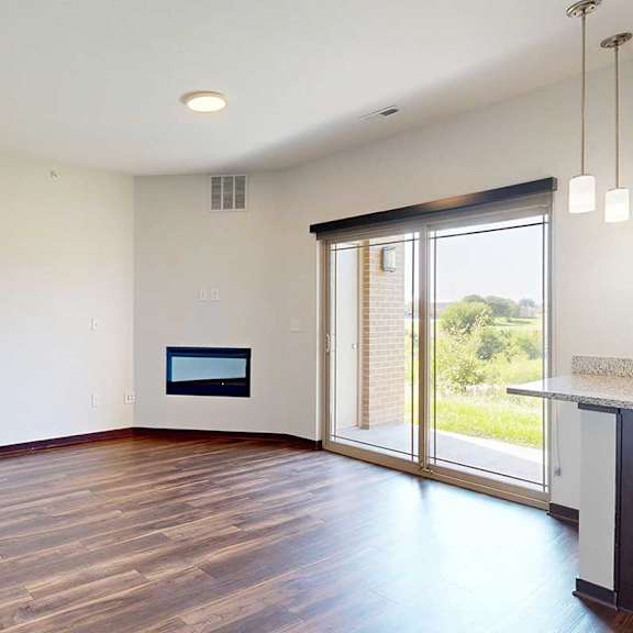 Thumbnail 17 of 29 A living room with hardwood flooring, an electric fireplace, and a sliding glass door to a patio.